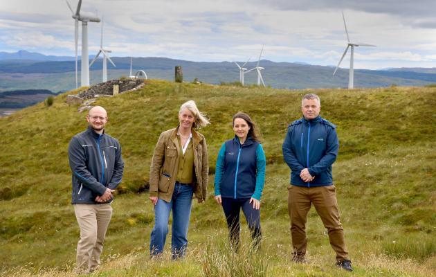 A group of four people standing in front of a windfarm