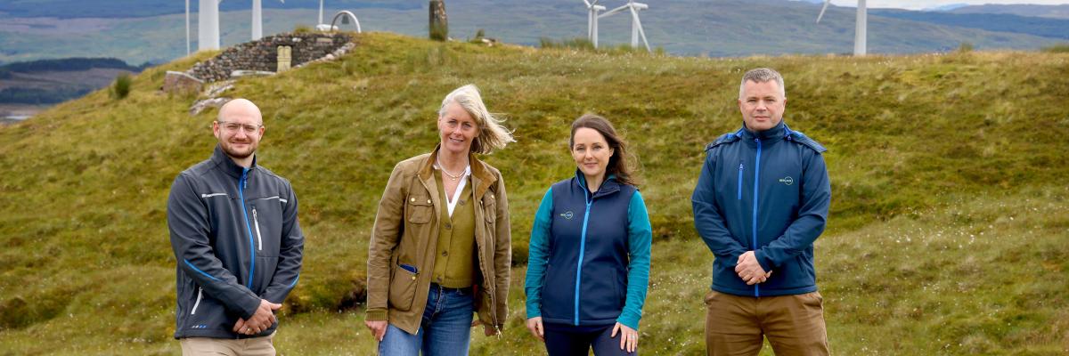 A group of four people standing in front of a windfarm